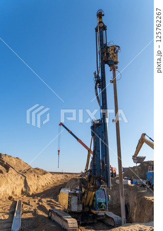 The yellow vibrating piling machine removes Larssen sheet piling from the ground The yellow vibrating piling machine removes Larssen sheet piling from the ground 125762267