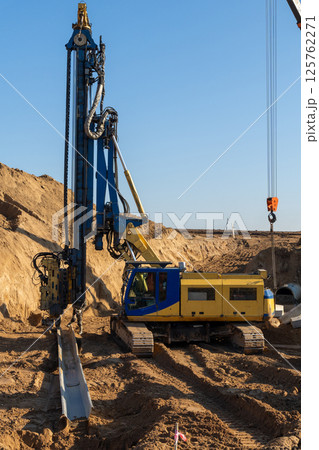 The yellow hydraulic piling machine lays Larsen dowels after extraction from the ground 125762271