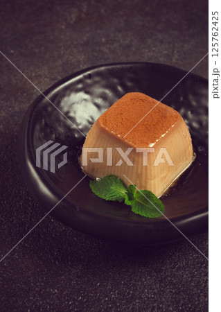 cream caramel pudding, with caramel sauce, dessert,breakfast, on a black plate, mint, no people, cream caramel pudding, with caramel sauce, dessert,breakfast, on a black plate, mint, no people, 125762425