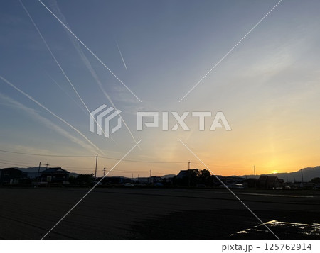 飛行機雲と山に沈む夕日 125762914