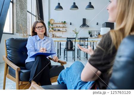 Female social worker working at home with young woman 125763120