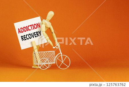 Addiction recovery symbol. Concept words Addiction recovery on beautiful white paper on clothespin. Beautiful orange table orange background. Psychology addiction recovery concept. Copy space. 125763762