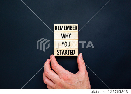 Remember why you started symbol. Concept word Remember why you started on wooden block. Beautiful black table black background. Businessman hand. Business remember why you started concept. Copy space. 125763848