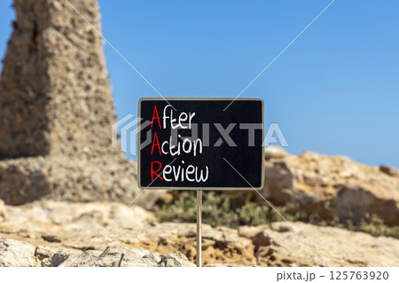 AAR After action review symbol. Concept words AAR After action review on beautiful yellow blackboard. Beautiful stone blue sky background. Business AAR after action review concept. Copy space. 125763920