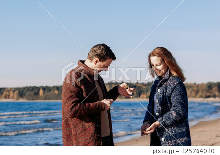 Loving couple walks on beach along sea on sunny autumn day. Weekend and lifestyle concept. High quality photo 125764010