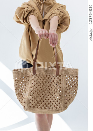 Female hand holding fashionable woven bag. Fashion and luxury accessories. Vertical photo. High quality photo Female hand holding fashionable woven bag. Fashion and luxury accessories. Vertical photo. High quality photo 125764030