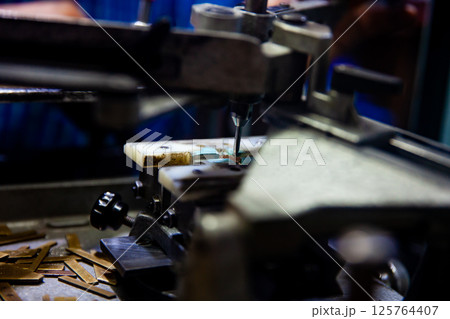 Close up of the process of Handcrafted engraving of texts on medals or jewelry. 125764407