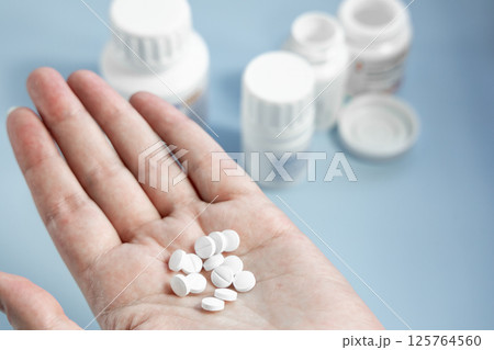 Human hand holding a handful of white pills Human hand holding a handful of white pills 125764560