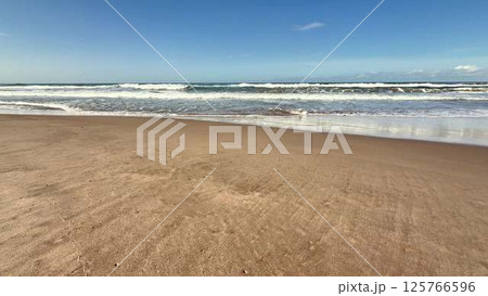 A Serene and Picturesque Beach Landscape Featuring Gentle Waves and Bright Clear Skies 125766596