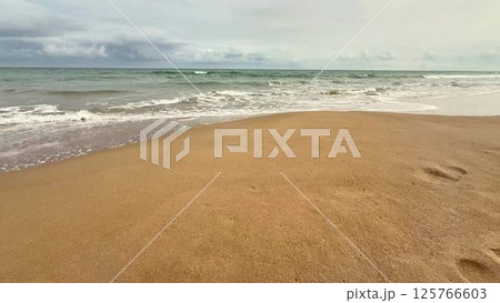 A beautifully serene seascape featuring a sandy beach with gentle waves softly lapping at the shore A beautifully serene seascape featuring a sandy beach with gentle waves softly lapping at the shore 125766603