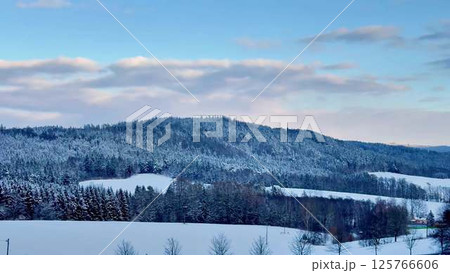 A Serene Winter Landscape Featuring Beautiful, SnowCapped Hills Against Clear Blue Skies 125766606