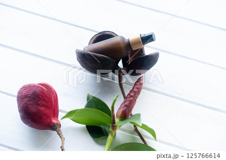 A cosmetic bottle with a pipette lies among vibrant natural items on a smooth surface. A cosmetic bottle with a pipette lies among vibrant natural items on a smooth surface. 125766614