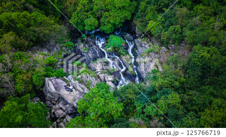 View of a Serene Waterfall Cascading Through Lush Green Forest 125766719