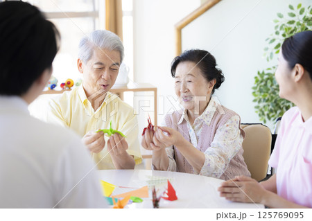 介護イメージ 折り紙を折るシニアと介護士 介護イメージ 折り紙を折るシニアと介護士 125769095