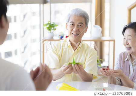 介護イメージ　折り紙を折るシニアと介護士 125769098