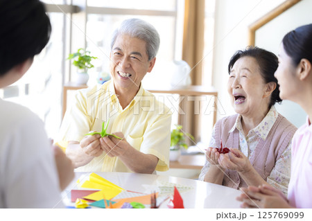 介護イメージ　折り紙を折るシニアと介護士 125769099