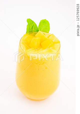 mango or peach smoothie with ice or fruit cubes served in transparent glass and topped with fresh mint leaves on white background. High quality photo mango or peach smoothie with ice or fruit cubes served in transparent glass and topped with fresh mint leaves on white background. High quality photo 125769928