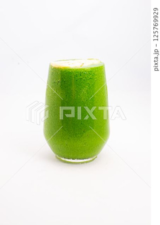 green smoothie with banana slices served in clear glass on white background healthy detox drink with tropical fruit topping. High quality photo green smoothie with banana slices served in clear glass on white background healthy detox drink with tropical fruit topping. High quality photo 125769929