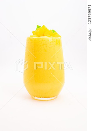 mango or peach smoothie with ice or fruit cubes served in transparent glass and topped with fresh mint leaves on white background. High quality photo mango or peach smoothie with ice or fruit cubes served in transparent glass and topped with fresh mint leaves on white background. High quality photo 125769971