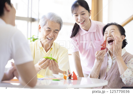介護イメージ　折り紙を折るシニアと介護士 125770036