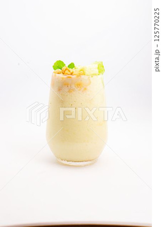 creamy banana smoothie topped with cereal flakes and fresh mint served in clear glass on white background. High quality photo 125770225