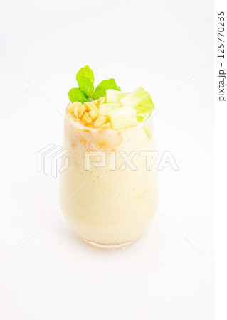 creamy banana smoothie topped with cereal flakes and fresh mint served in clear glass on white background. High quality photo creamy banana smoothie topped with cereal flakes and fresh mint served in clear glass on white background. High quality photo 125770235