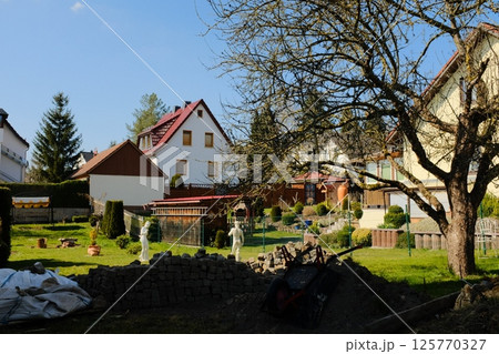 european village garden decorated with white easter bunny statues and spring greenery under clear sky. High quality photo 125770327