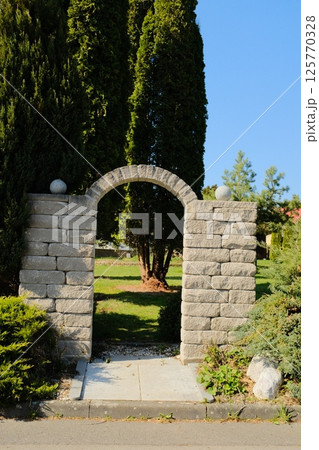 european village garden decorated with white easter bunny statues and spring greenery under clear sky. High quality photo 125770328