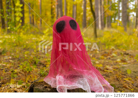 Halloween holiday concept. Handmade pink ghost made from bandages and glue in autumn forest background. Children's art project. DIY 125771866