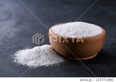 salt in a wooden bowl on a black stone table, selective focus. 125772866