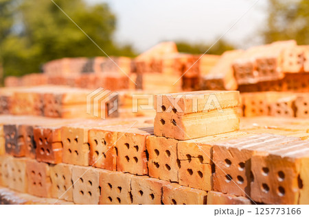 Red bricks stacked at a construction site, close-up. at the building site, red keramoblock hollow bricks Close up of the red brick used in the construction of the building's walls and partitions. Red bricks stacked at a construction site, close-up. at the building site, red keramoblock hollow bricks Close up of the red brick used in the construction of the building's walls and partitions. 125773166