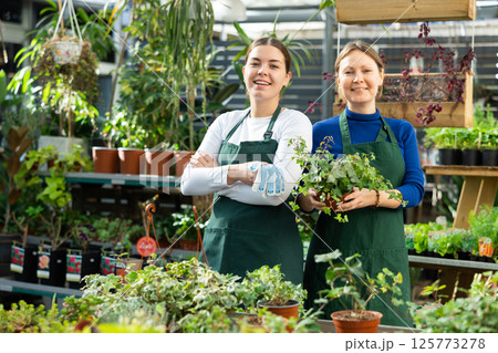 Adult woman and young woman posing in flower shop Adult woman and young woman posing in flower shop 125773278