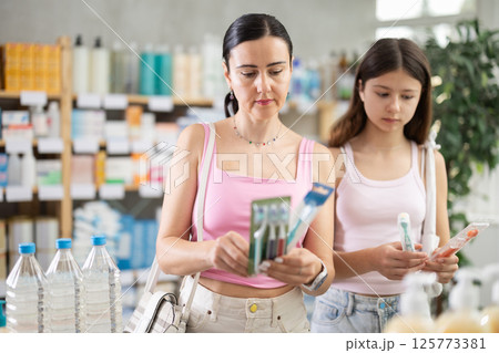 Mom and daughter client choosing toothbrush in drugstore 125773381