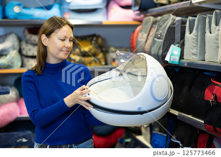 Female dog owner choosing portable carrier in pet shop 125773466