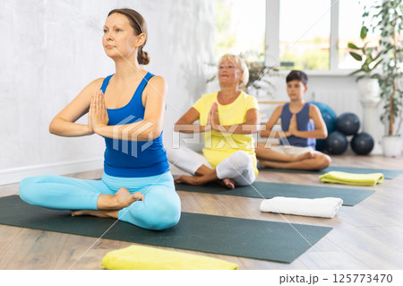 Group of people generation on mats doing yoga exercise lord of fishes pose. 125773470