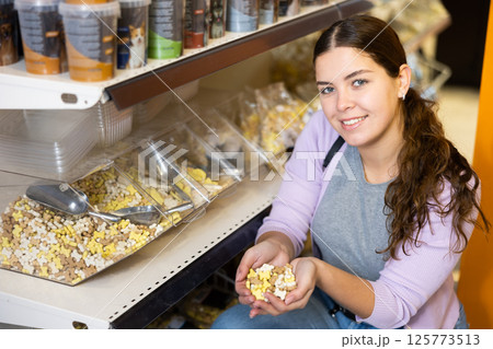 Woman holding handful of dry food for dog in pet store 125773513