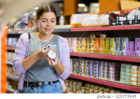 Young woman scanning label on tin can of wet food in pet store Young woman scanning label on tin can of wet food in pet store 125773545