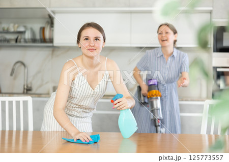 Young girl cleaning the table surface, mother vacuum-cleaning in the kitchen 125773557