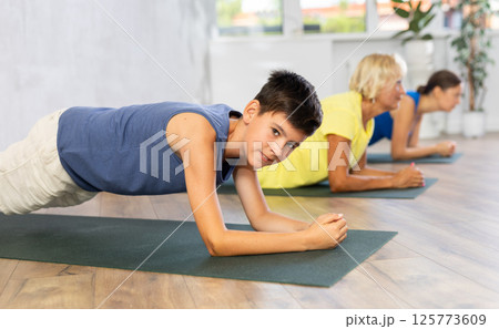 Preteen boy practicing plank pose of yoga in light fitness room 125773609