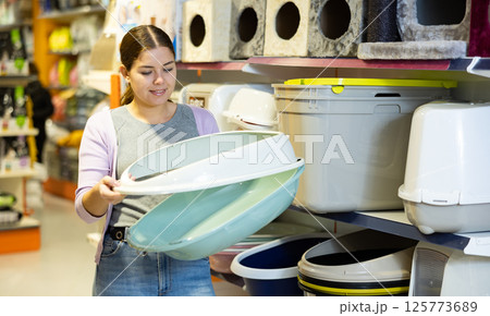 Female cat owner choosing plastic litter tray in pet shop Female cat owner choosing plastic litter tray in pet shop 125773689