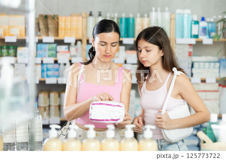 Woman with teen girl choose buy panty liners at pharmacy 125773722