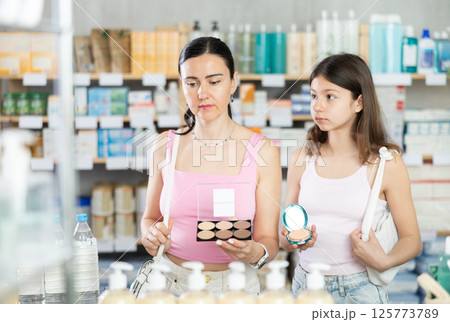 Mom and daughter choosing cosmetics in chemist's shop Mom and daughter choosing cosmetics in chemist's shop 125773789