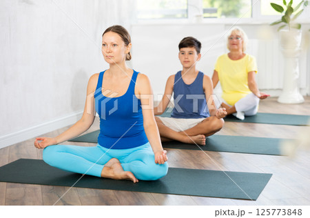 Family three generations do half lotus position Sidhasana with hands clasped in mudra of knowledge 125773848