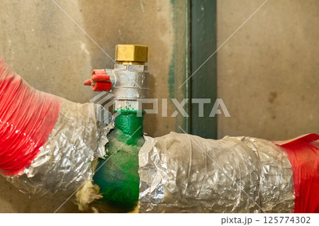 Water supply.Valve shutting,pipes wrapped with insulation in basement Water supply.Valve shutting,pipes wrapped with insulation in basement 125774302