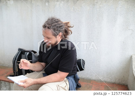 Journalist writing notes outdoors, taking a break from reporting 125774623