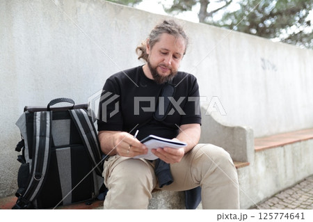 Writer taking notes outdoors in urban setting Writer taking notes outdoors in urban setting 125774641