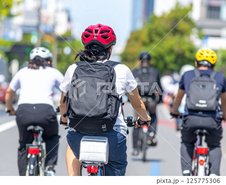 ヘルメットをかぶって自転車を漕ぐ人 125775306
