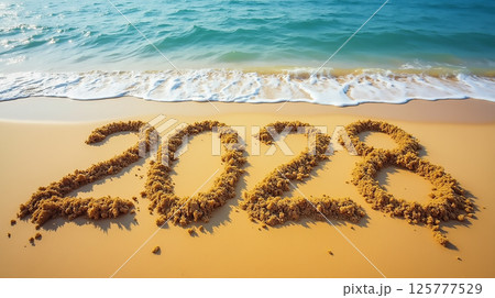 Sand inscription of 2028 on a beach shore with gentle waves lapping at the sandy surface 125777529