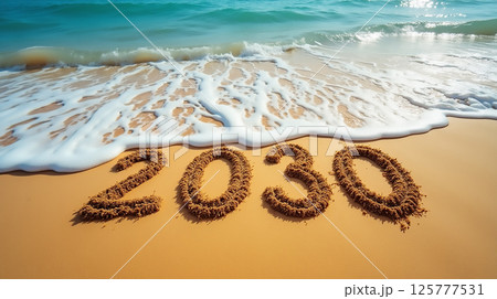 Waves softly wash over sandy beach with 2030 marked in the sand on a sunny day 125777531