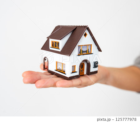 Woman is holding a mini toy house in her hand. Real estate concept. Woman is holding a mini toy house in her hand. Real estate concept. 125777978